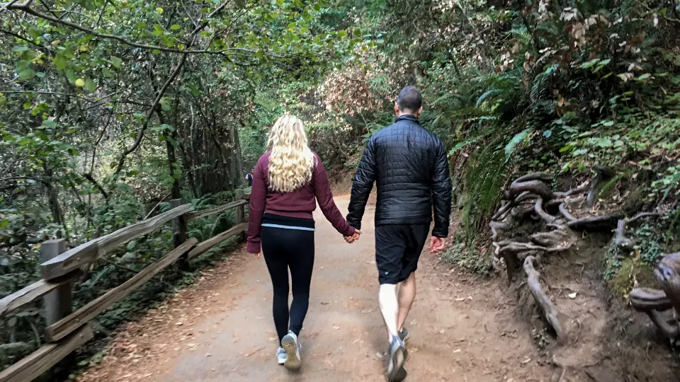 Two people walking together along a quiet path through the trees