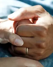 Two people sitting together with their hands gently clasped