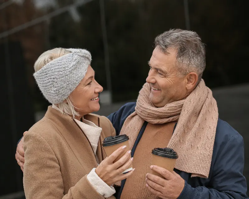 An older couple standing close together outdoors, smiling